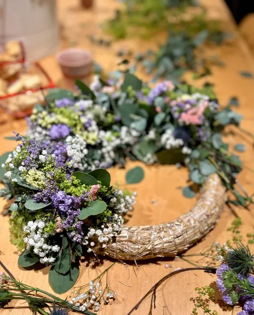 Floral wreath in progress on wooden table.