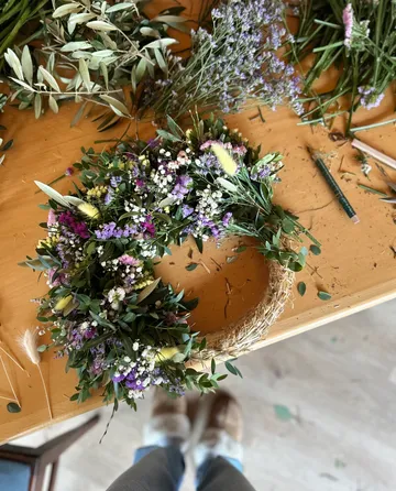 Floral wreath on table with greenery.