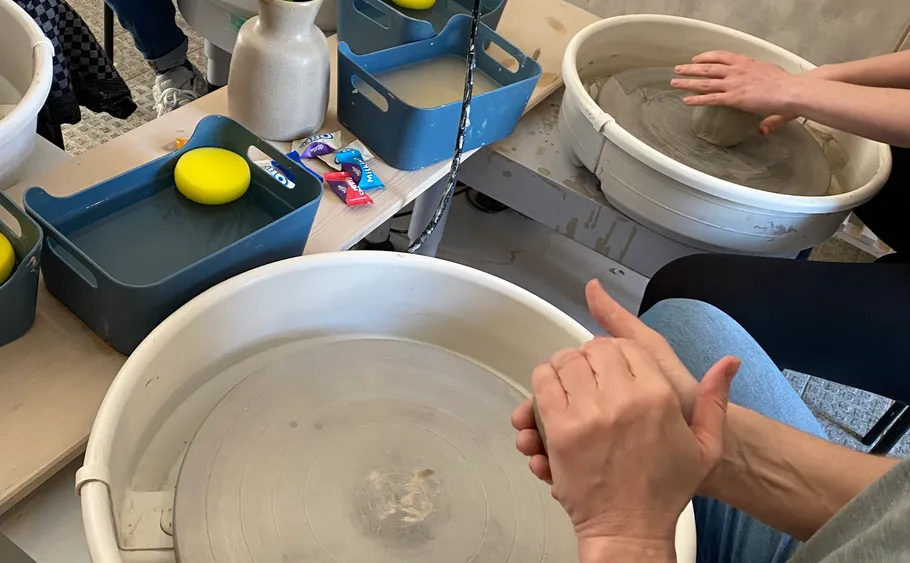 Hands shaping clay on pottery wheel in studio.