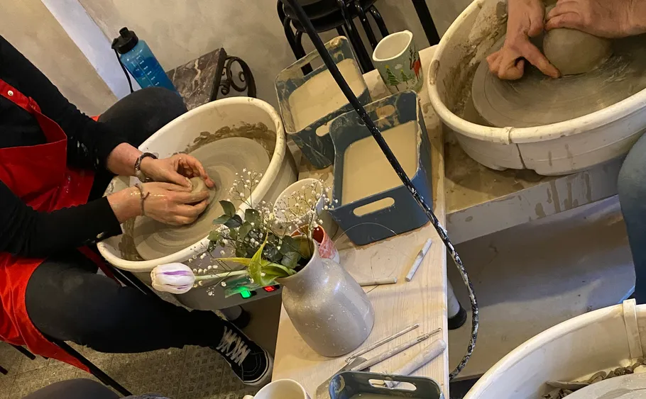 People shaping clay on pottery wheels indoors.