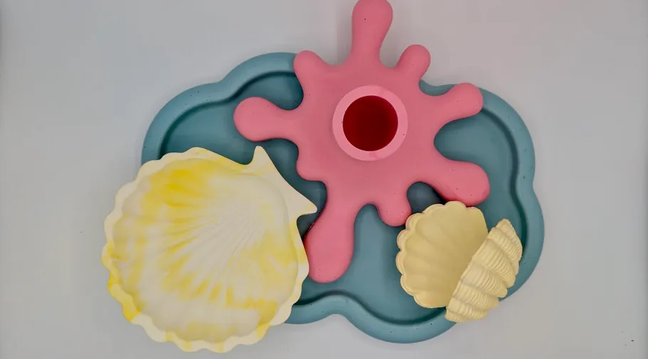 Bunte Muscheln auf blauem Tablett, pinker Ausguss.