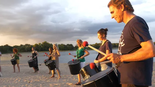 Menschen trommeln am Strand bei Sonnenuntergang.