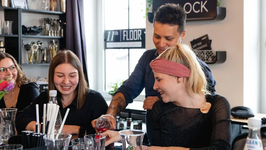 People smiling while making cocktails at a bar.