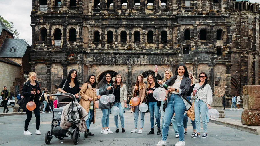 Group of women with balloons in front of ancient arch.