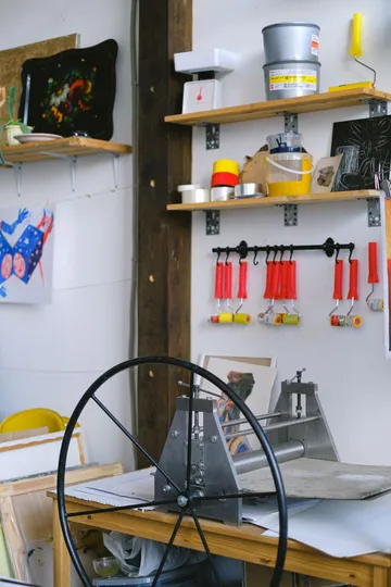 Kunststudio mit Druckpresse und Regalen.