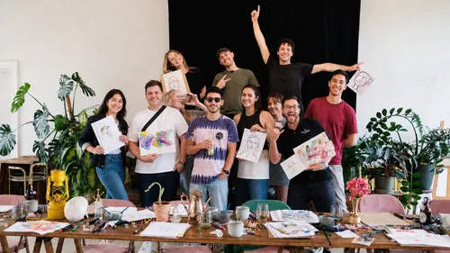 Gruppe posiert mit Kunstwerken im Studio.
