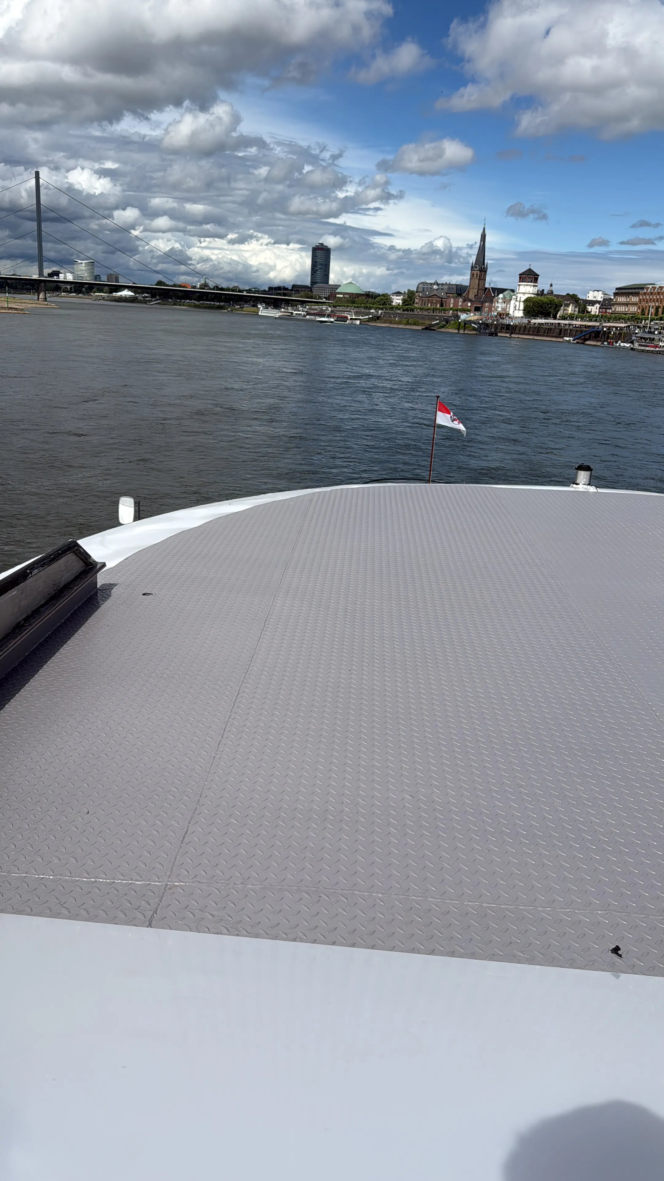 Schiffsdeck mit Stadtblick, bewölkter Himmel.