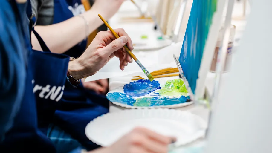 Person painting with blue and green colors in studio.