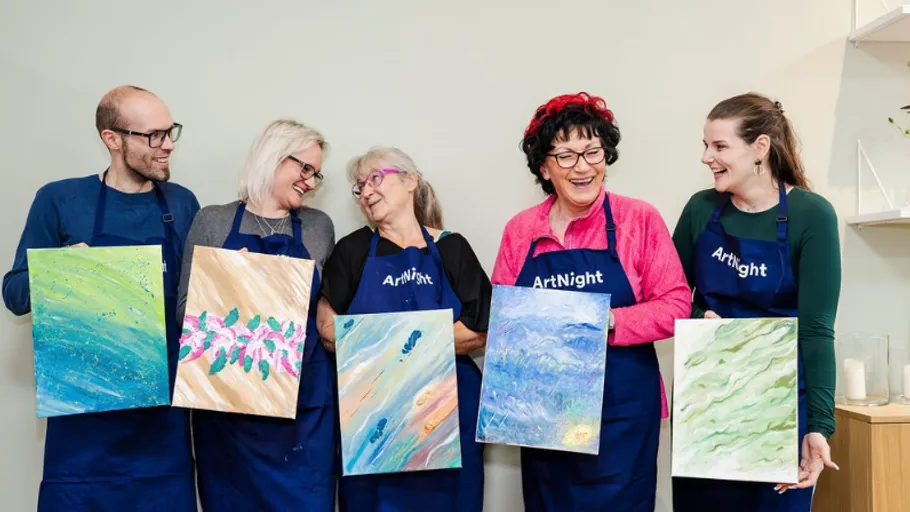 Five people holding painted canvases, smiling indoors.