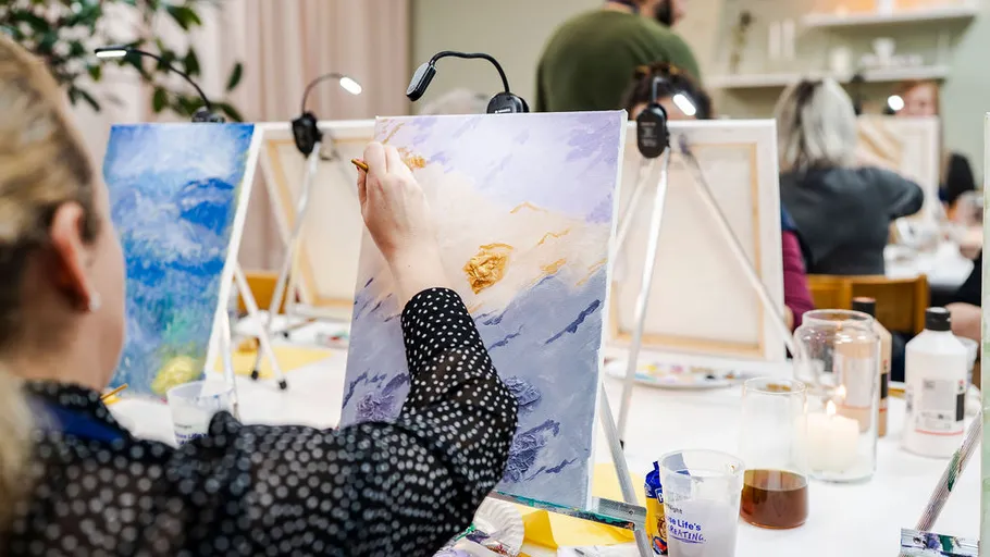 Person painting on canvas in an art class.