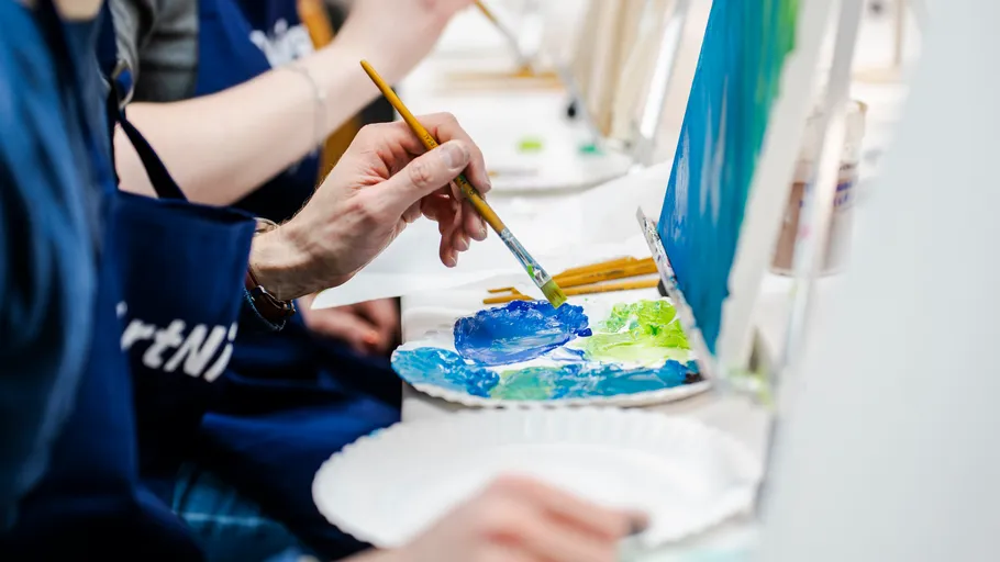 Person painting on canvas in art class.