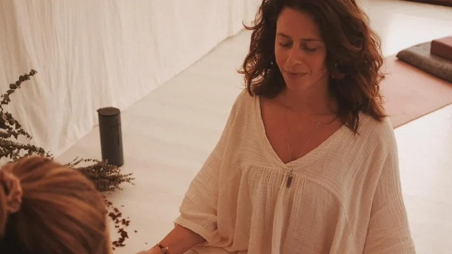 Woman meditating in a peaceful indoor setting.