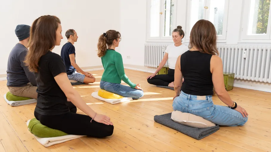 People meditating in a bright yoga studio.