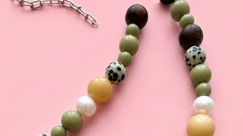 Perlenkette mit gemischten Farben auf rosa Hintergrund.