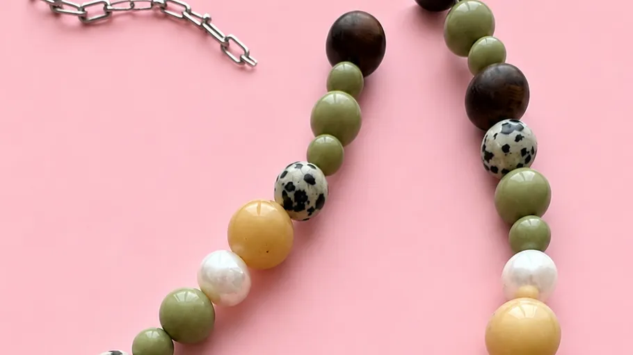 Perlenkette mit gemischten Farben auf rosa Hintergrund.