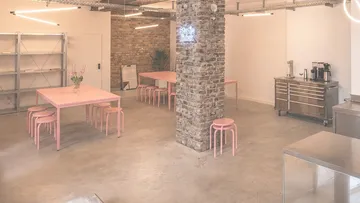 Modern studio with pink tables and kitchen.
