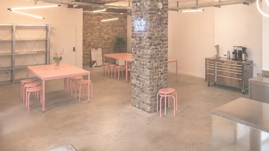Modern studio with pink tables and kitchen.