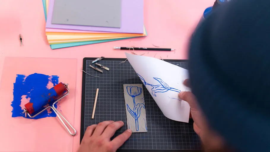 Person creating floral print with ink and paper.