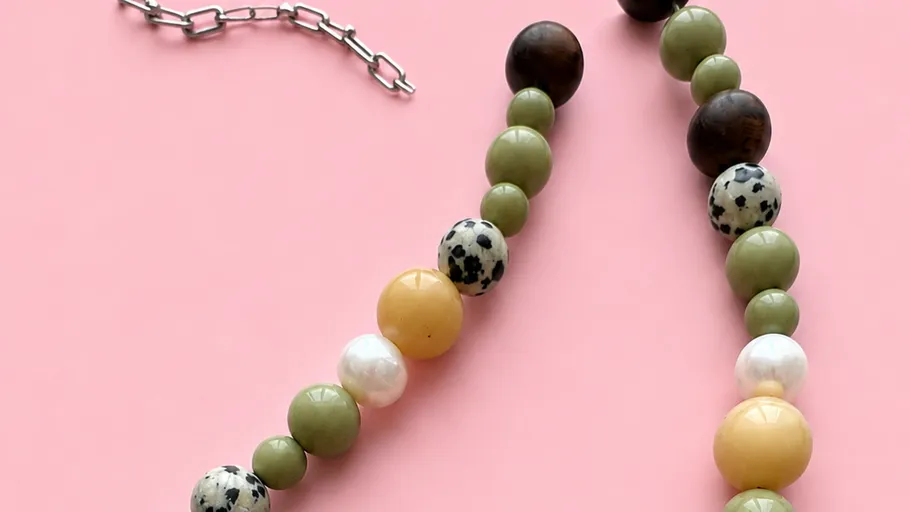 Colorful bead necklace on pink background.