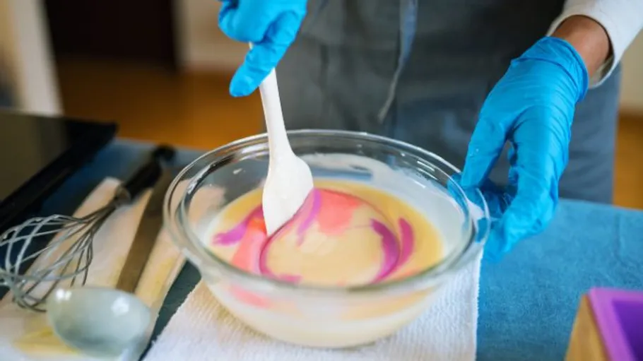 Person mixes colorful batter in glass bowl.