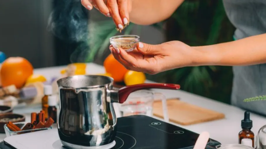 Person adding spices to boiling pot indoors.