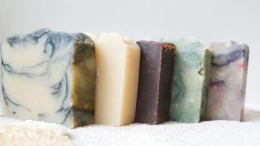 Five colorful soap bars on a towel.