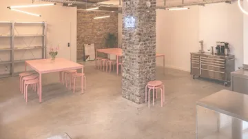 Modern dining area with pink tables and chairs.