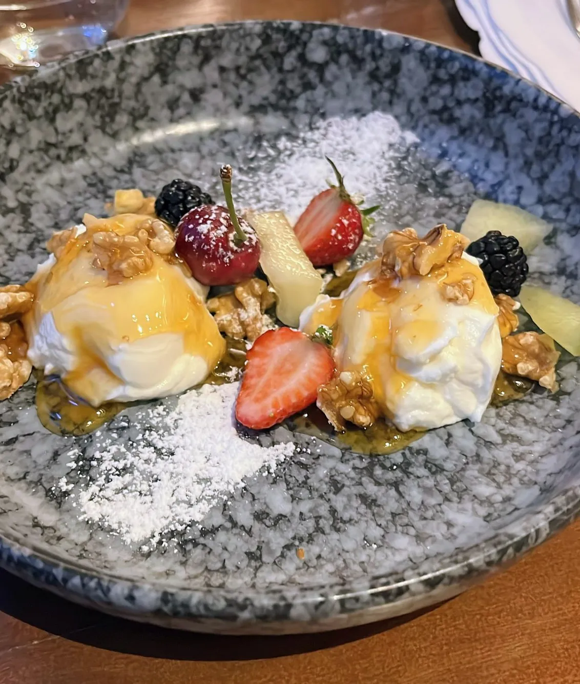 Dessert mit Früchten und Nüssen auf Teller.