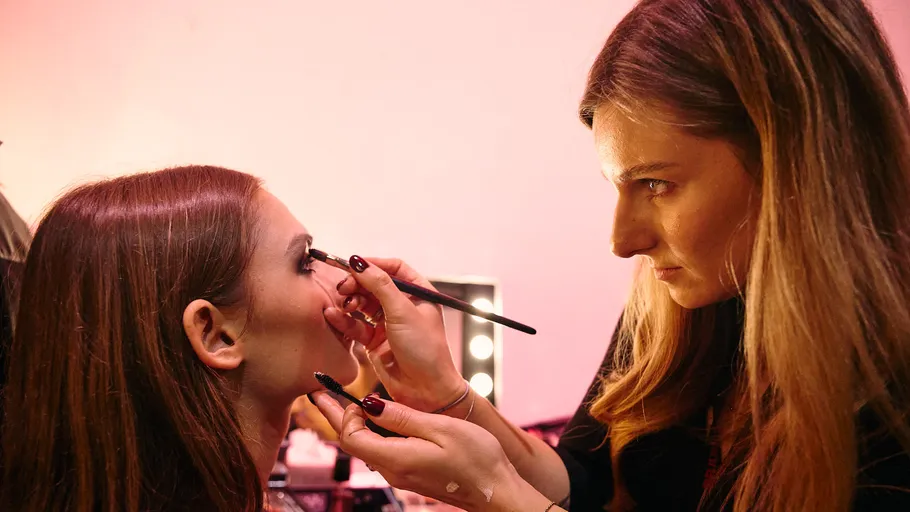 Makeup artist applies eyeshadow on woman backstage.