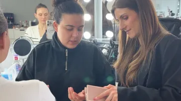 Two women discussing makeup palette in a studio.