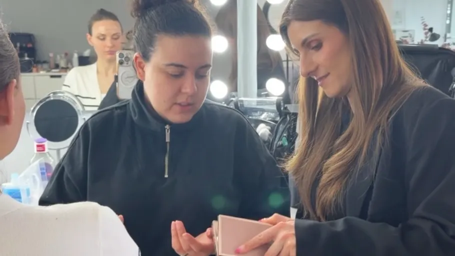 Two women discussing makeup palette in a studio.
