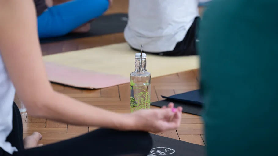 Personen in Yogakurs mit Wasserflasche.