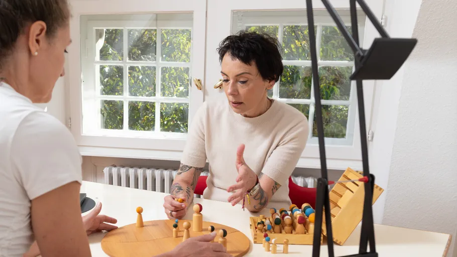 Two women discussing over a wooden board game.