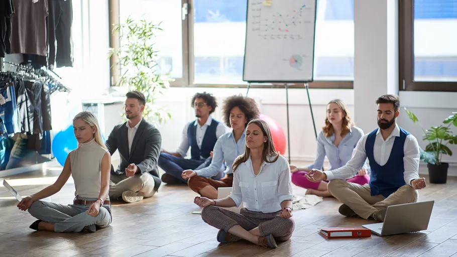 Group meditating in office with laptops around.
