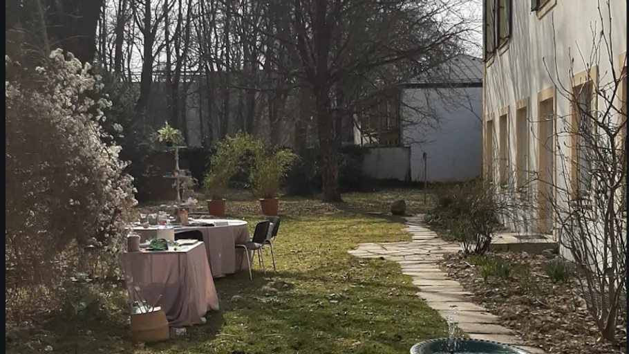 Outdoor garden table with chairs, house nearby.
