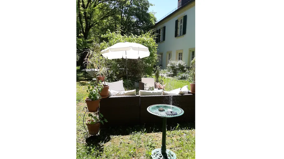 Gartenpatio mit Sonnenschirm und Sitzgelegenheiten.