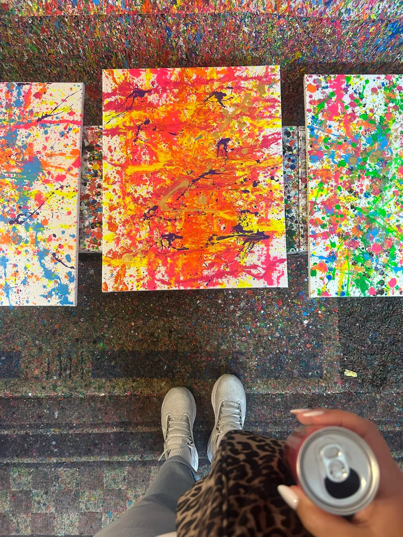 Abstract paintings and person holding a drink.