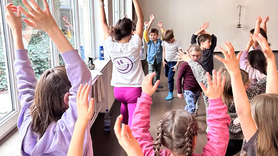 Kinder und Trainer machen Yoga in einem Raum.
