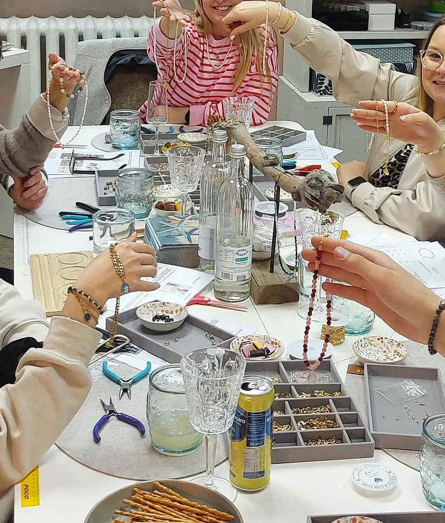 People making jewelry at a workshop table.