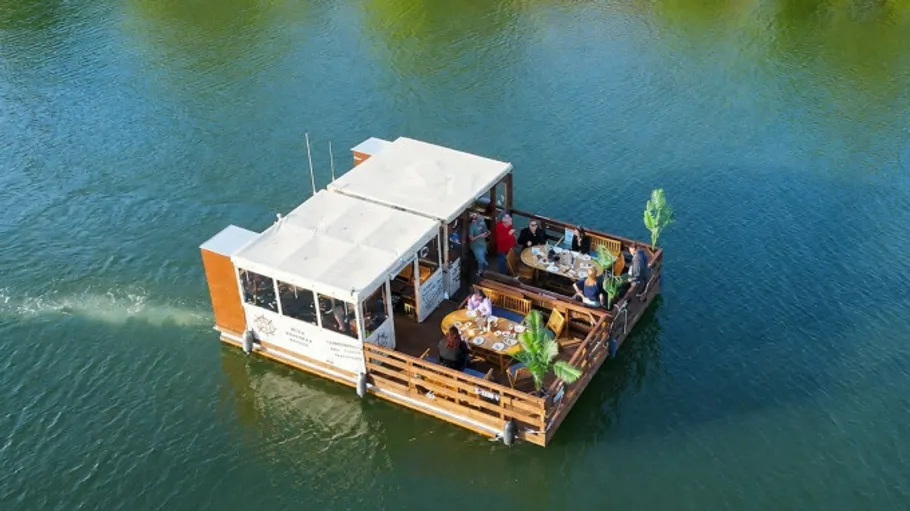 Schwimmende Essplattform mit Menschen auf einem Fluss.
