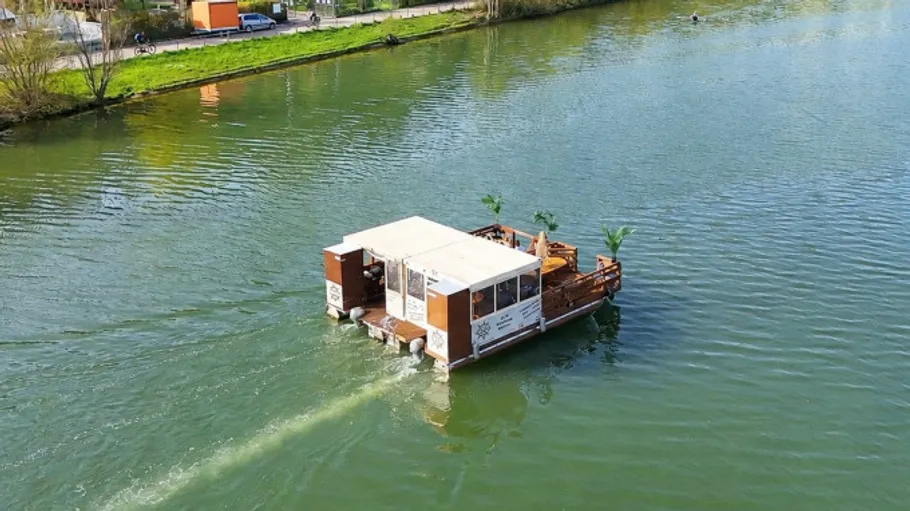 Floating houseboat travels on a river.