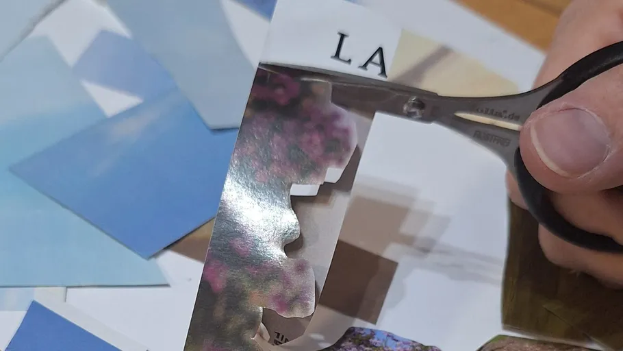 Hand cutting paper with scissors on table.