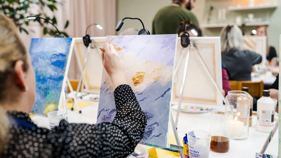 Woman painting in art class with easels.