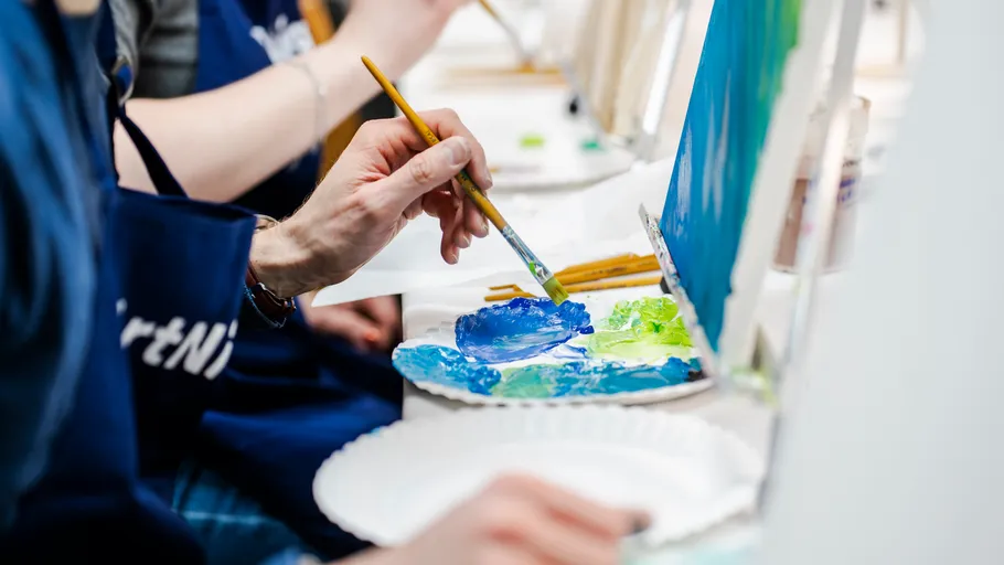 Person painting with brushes and palette.