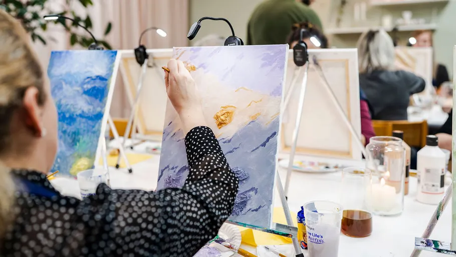 Person painting on canvas in art class.