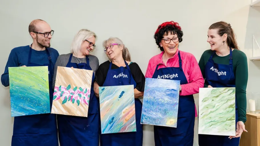 Five people holding paintings, smiling together.