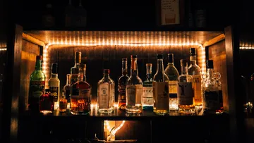 Assorted liquor bottles on shelf with backlighting.