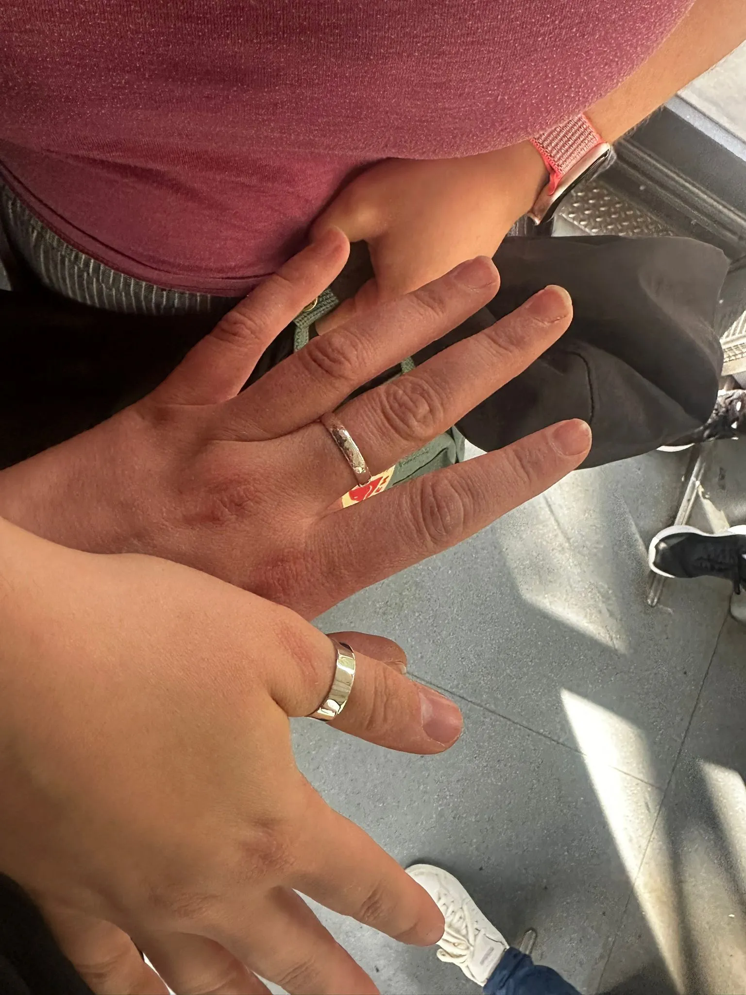 Hands with rings on gray floor.