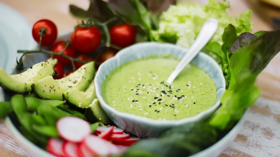 Green dip surrounded by fresh vegetables.