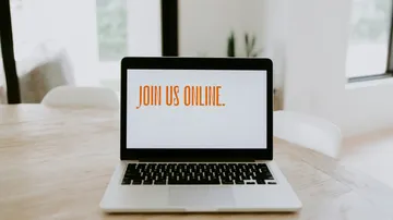 Laptop displaying 'JOIN US ONLINE', room setting.